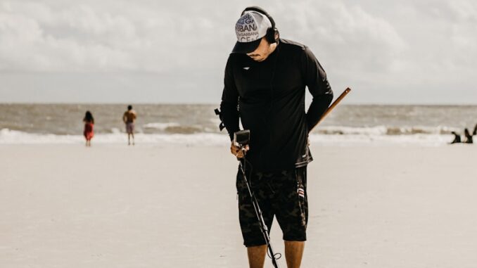 a man standing on a beach holding a baseball bat