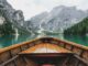 brown wooden boat moving towards the mountain