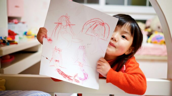 girl holding paper with drawing